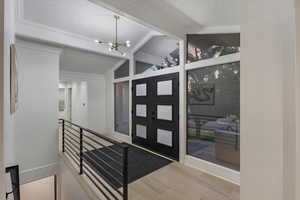 Entryway featuring light hardwood / wood-style flooring, vaulted ceiling with beams, and an inviting chandelier