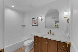 Full bathroom featuring toilet, tiled shower / bath combo, vanity, and tile patterned flooring