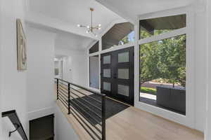 Entryway with lofted ceiling with beams, light wood-type flooring, a chandelier, and a healthy amount of sunlight