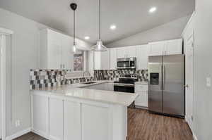 Kitchen with white cabinetry, hanging light fixtures, backsplash, stainless steel appliances, and dark hardwood / wood-style flooring