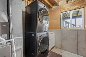 Washroom with cabinets and stacked washing maching and dryer