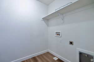 Laundry area with hookup for a washing machine, hardwood / wood-style flooring, and hookup for an electric dryer