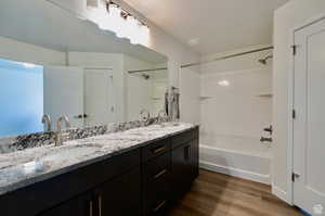 Bathroom featuring wood-type flooring, double vanity, and shower / tub combination