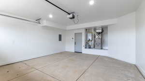 Garage with electric panel, heating unit, and a garage door opener