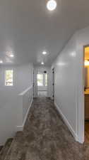Hallway featuring dark carpet