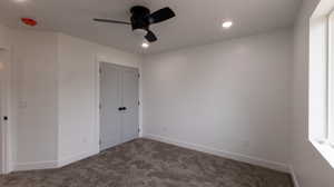 Unfurnished bedroom featuring dark colored carpet, ceiling fan, and a closet