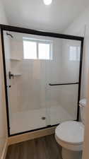 Bathroom featuring hardwood / wood-style flooring, toilet, and walk in shower