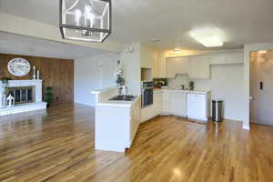 Kitchen featuring a brick fireplace, light hardwood / wood-style flooring, sink, and oven