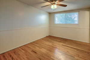 Empty room with a textured ceiling, ceiling fan, and light hardwood / wood-style floors