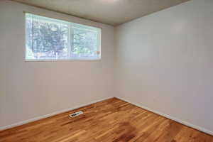 Unfurnished room featuring a textured ceiling and light wood-type flooring