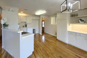 Kitchen with light hardwood / wood-style flooring, white cabinets, sink, and dishwasher