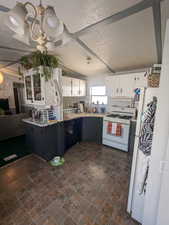 Kitchen with a textured ceiling, white appliances, and white cabinetry