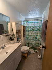 Bathroom with tasteful backsplash, a textured ceiling, vanity, and toilet