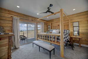 Carpeted bedroom with wood walls, access to exterior, and recessed lighting