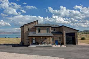 View of front of house with roof with shingles, a garage, and a water and mountain view