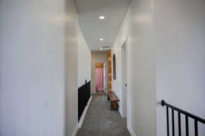 Hallway featuring an upstairs landing and dark carpet