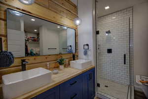 Bathroom with a stall shower, double vanity, a spacious closet, and recessed lighting