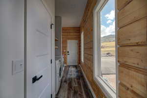 Laundry room with washing machine and dryer, wood walls, plenty of natural light, dark wood finished floors, and a mountain view