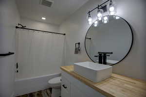 Full bath with vanity, shower / bath combo with shower curtain, and wood finished floors