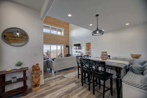 Dining room with a towering ceiling, wood finished floors, recessed lighting, and wooden walls