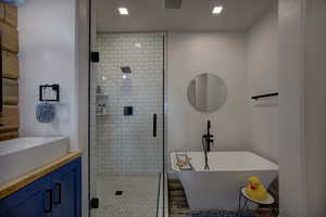 Bathroom with a stall shower, a soaking tub, and vanity