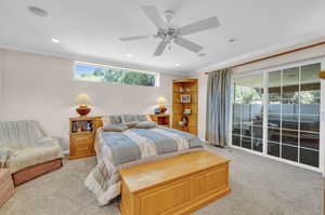 Carpeted bedroom with crown molding, ceiling fan, and multiple windows