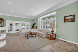 Living room featuring french doors, ornamental molding, and light colored carpet