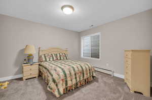 Carpeted bedroom with a baseboard heating unit