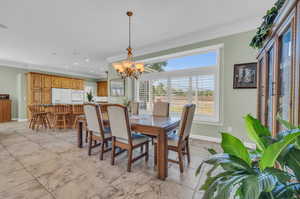 Dining room featuring light tile patterned floors, a chandelier, and crown molding