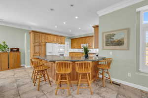 Kitchen with white appliances, a breakfast bar area, decorative backsplash, and light tile patterned floors