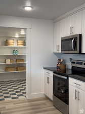 Kitchen featuring appliances with stainless steel finishes, light hardwood / wood-style flooring, a textured ceiling, and light brown cabinets