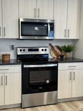 Kitchen with tasteful backsplash, stainless steel appliances, light hardwood / wood-style floors, and light brown cabinets