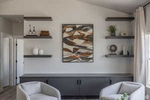 Living area featuring dark wood-type flooring and vaulted ceiling