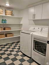 Laundry area featuring light tile patterned floors, washing machine and dryer, a textured ceiling, and cabinets