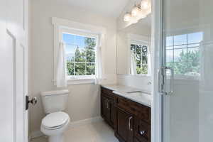 Guest house bathroom with tile patterned floors, a healthy amount of sunlight, and toilet