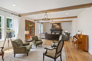 Living room featuring an inviting chandelier, beamed ceiling, and light hardwood / wood-style floors