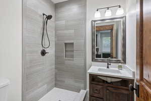 Bathroom featuring vanity, toilet, and tiled shower