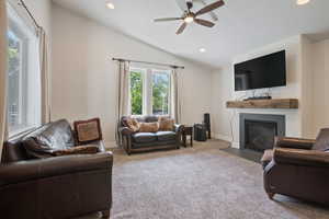 Guest house living room featuring ceiling fan, vaulted ceiling, and carpet flooring