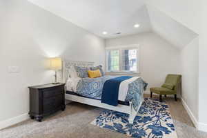 Guest house carpeted bedroom featuring vaulted ceiling