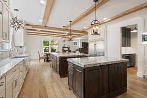 Kitchen featuring built in appliances, light hardwood / wood-style flooring, a kitchen island, and decorative backsplash