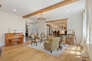 Living room with a chandelier, beam ceiling, and light hardwood / wood-style floors