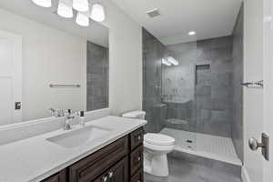 Bathroom featuring toilet, tile patterned floors, vanity, and a shower with shower door