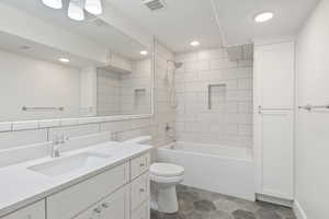 Full bathroom with tile walls, tiled shower / bath, toilet, tile patterned floors, and vanity