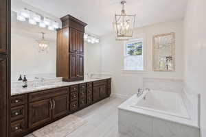 Bathroom featuring double sink vanity, tile patterned floors, a relaxing tiled tub, and an inviting chandelier