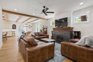 Living room featuring a fireplace, ceiling fan with notable chandelier, plenty of natural light, and light hardwood / wood-style floors