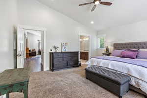 Guest house bedroom with ceiling fan, hardwood / wood-style flooring, connected bathroom, and vaulted ceiling