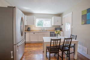 Kitchen with dark hardwood / wood-style floors, stainless steel appliances, and white cabinetry