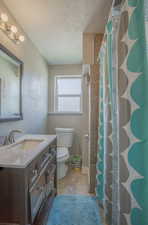 Bathroom featuring a textured ceiling, toilet, tile patterned floors, and vanity