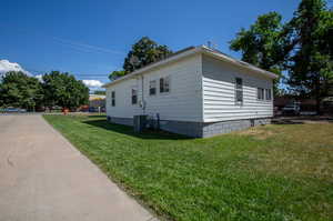 View of property exterior featuring central air condition unit and a lawn