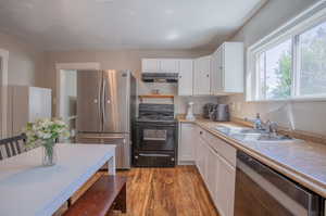 Kitchen with light hardwood / wood-style flooring, appliances with stainless steel finishes, sink, and white cabinets